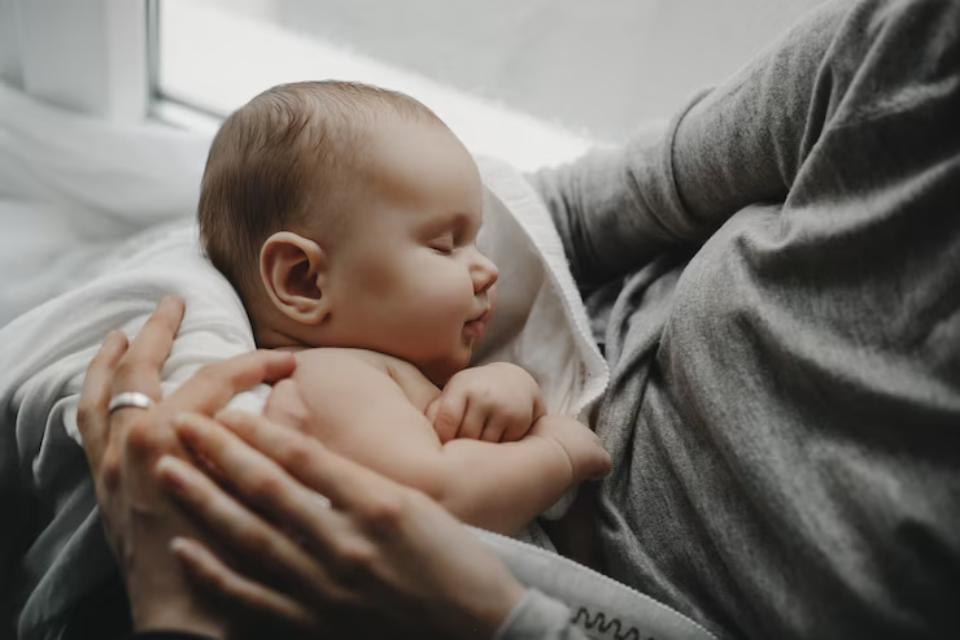  A close-up of a baby wrapped in a soft blanket, cradled in a parent's arms, with a serene atmosphere and soft natural light.