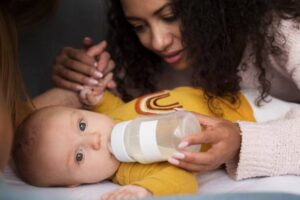 A caregiver gently feeds a child with a bottle while holding their hand, creating a peaceful and nurturing atmosphere.