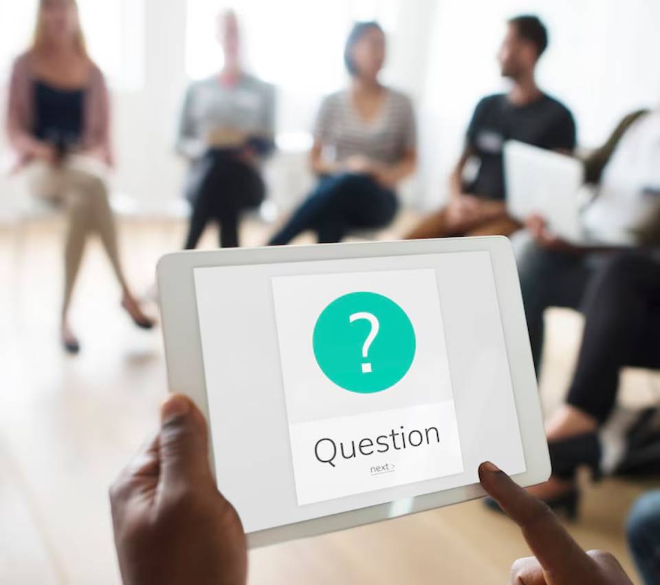 A person holds a tablet displaying a question mark and the word 