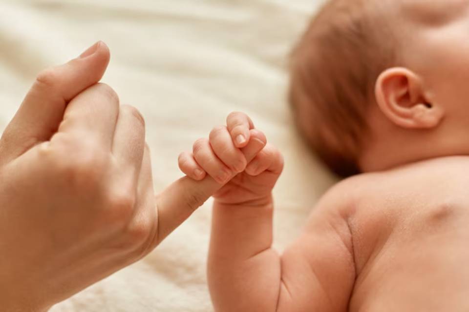 A close-up of a baby's hand grasping a parent's finger, showcasing a tender moment of connection and affection.