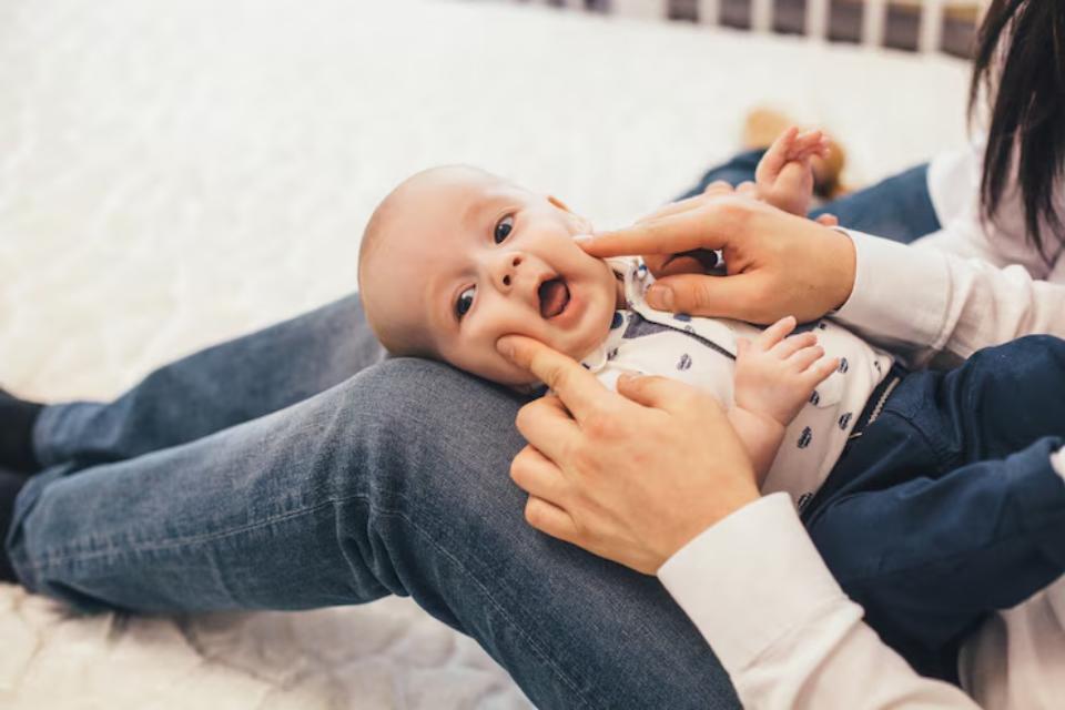  A close-up of hands gently interacting with a baby sitting on a person's lap, showcasing a warm and nurturing environment.