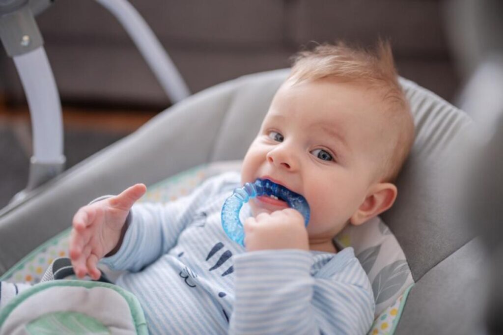 A cozy baby in a blue striped onesie sits in a gentle swing, reaching out curiously with one hand. Soft, blurred background ambiance.